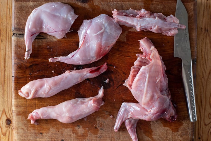 wooden board with one wild rabbit butchered into various pieces