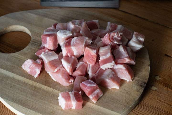 wooden board with diced pork belly on