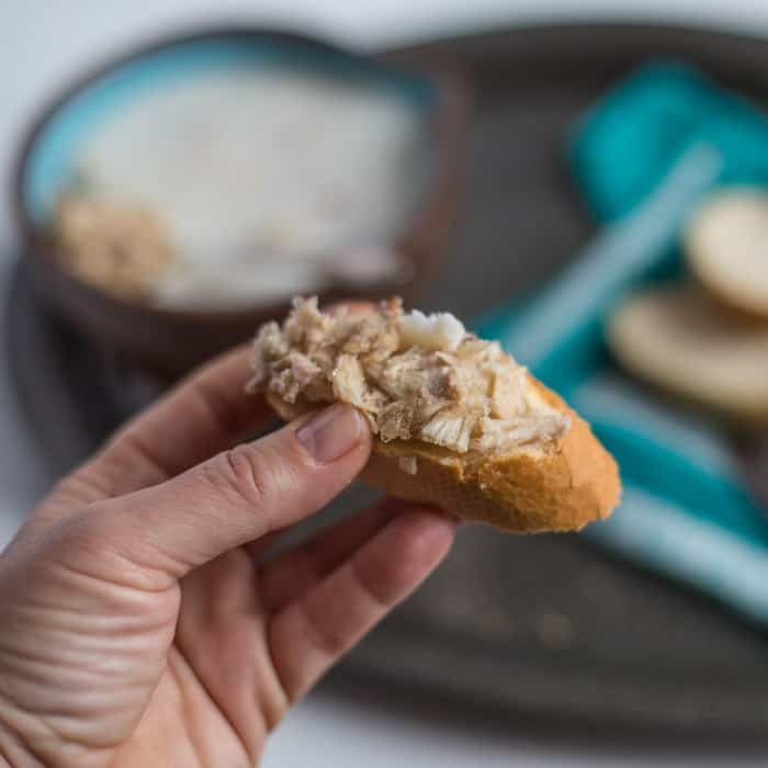 Rabbit Rillettes on a slice of crusy bread held ready to be eaten 