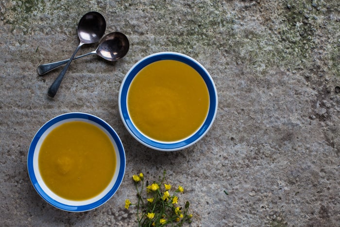 2 bowls of Leek and Sweet Potato Soupwith 2 spoons on a snowy background