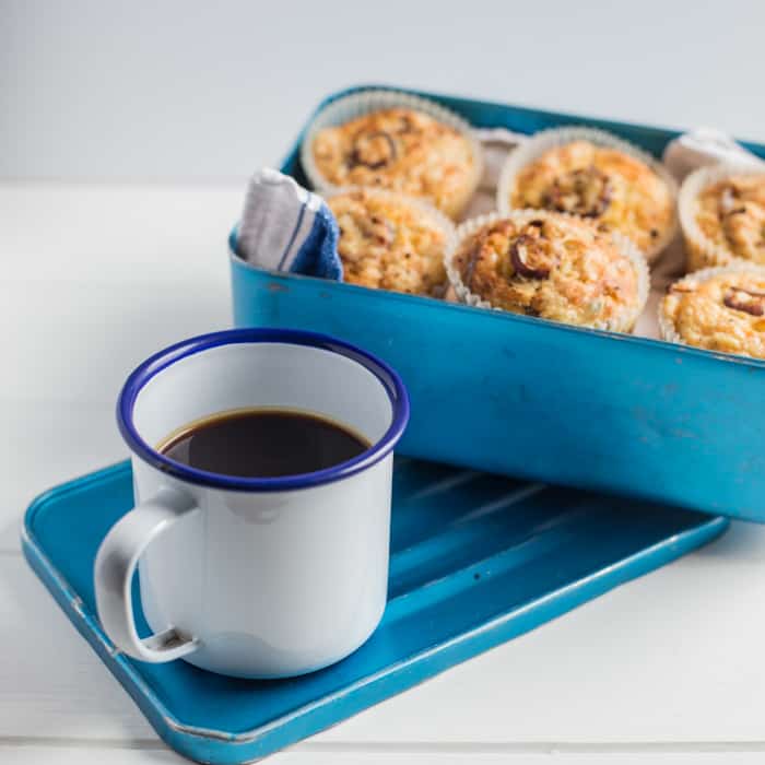 Cheese and Red Onion Muffins in a bluebox beside a mug of black coffee