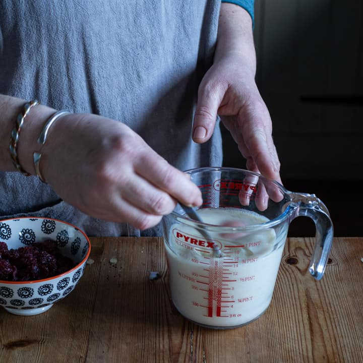 womands hands stirring the wet ingredients of a muffin recipe in a glass jug