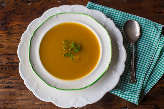 Leek and Butternut Squash Soup in a white bowl with a soup spoon and a green and white check cloth