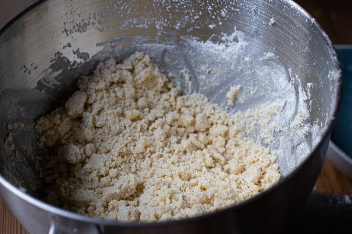 close up of shortbread crumbs in a silver mixing bowl