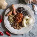 small white plate with whole madras curry spices