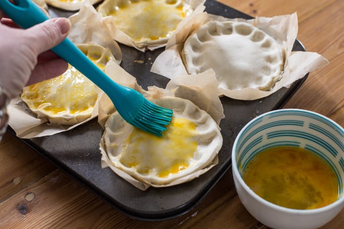 Chilli Beef Pies being brushed with egg wash 