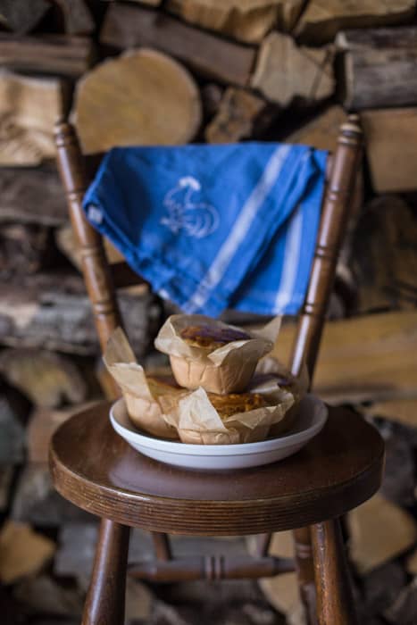 Chilli Beef Pies piled up on a white plate on a wooden chair with a blue cloth