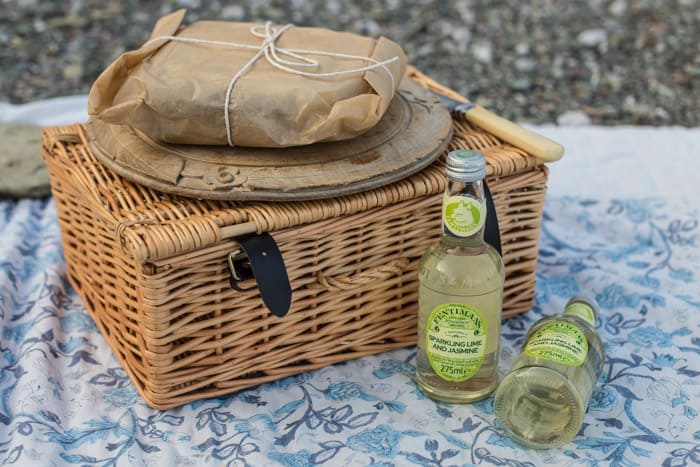 Pressed Picnic Sandwich on a bread board on top of a picnic basket with bottles of Fentimens beside 