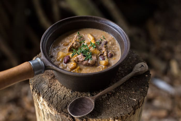 Slow Cooker Pepperpot Stew Recipe in a pan on a piece of wood with a serving spoon