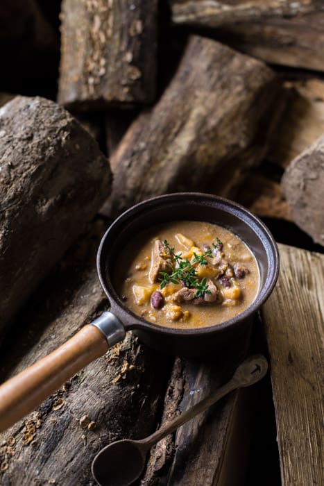Slow Cooker Pepperpot Stew in a pan on a piece of wood with a serving spoon