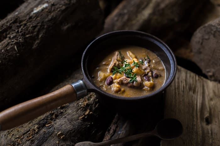 Slow Cooker Pepperpot Stew recipe cooked in a pan on a piece of wood 