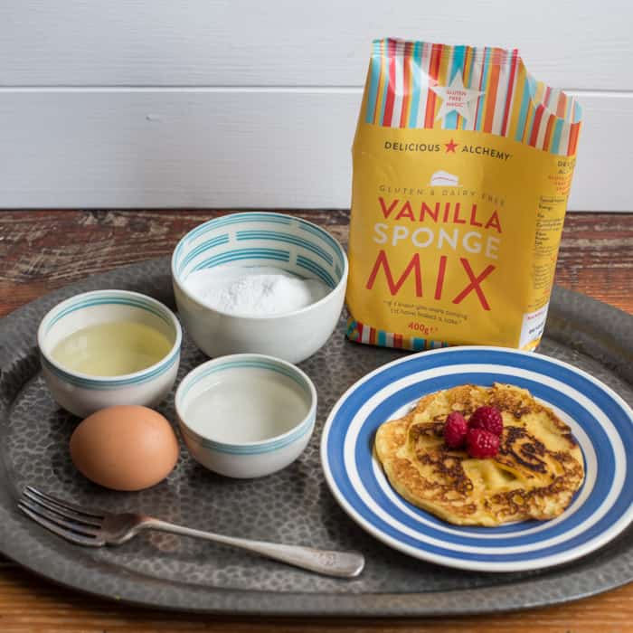 Gluten free camping breakfast recipe -Vanilla Puffy Pancakes on a blue and white plate surrounded by ingredients on a metal tray