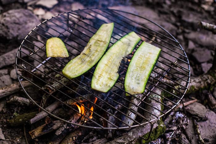 Beach campfire with 4 slices of courgette grilling over the embers