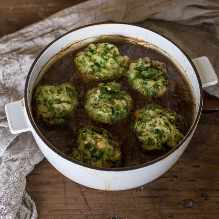 casserole dish containing beef in guinness with wild garlic mushrooms on a wooden table with a white cloth