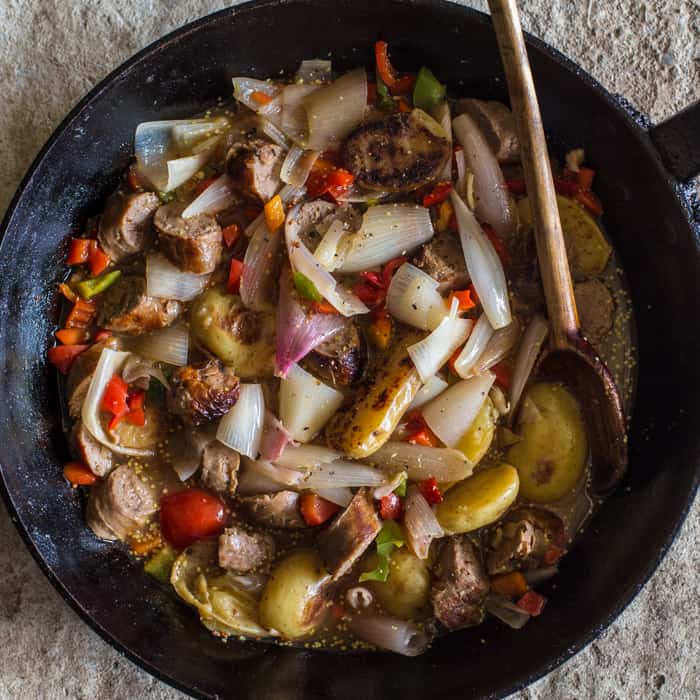 Sausage and Cider Campfire Skillet with a wooden spoon