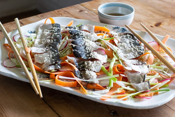 blue and white platter of salad and raw mackerel with chopsticks on the side