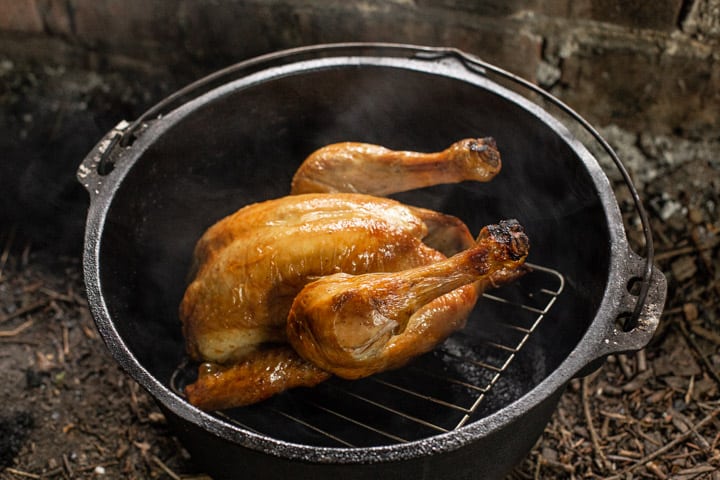 Golden brown roast chicken inside a cast iron dutch oven