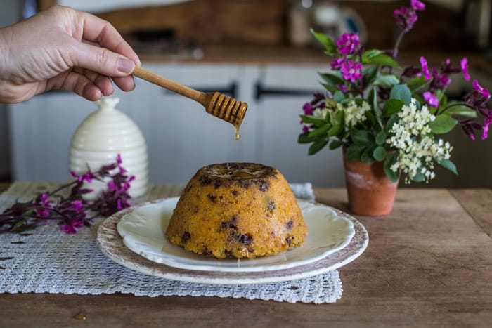 Snowdon Pudding on a white plate being drizzled with honey