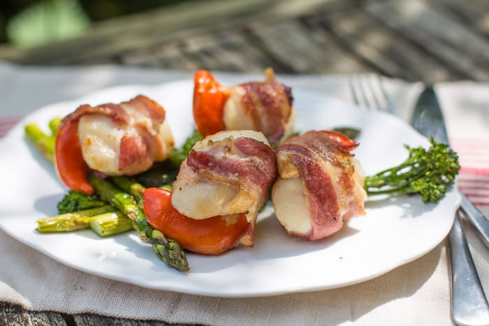 BBQ Scallops in Bacon on a white plate with asparagus spears