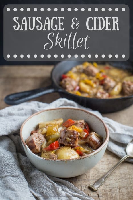 white bowl of hearty sausage and cider campfire skillet with a cast iron skillet in the background