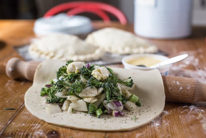 Tenderstem and Cornish Blue Cheese Pasty filling on pastry round with a rolling pin on a floured table with tenderstem and baking equipment