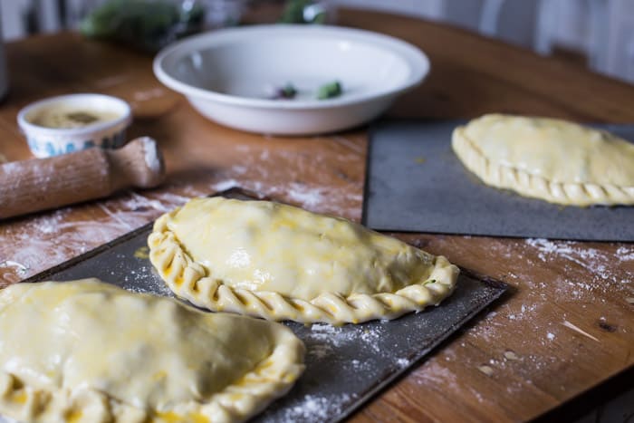 Tenderstem and Cornish Blue Cheese Pasty on baking trays crimped ready to go in the oven surrounded by baking equipment