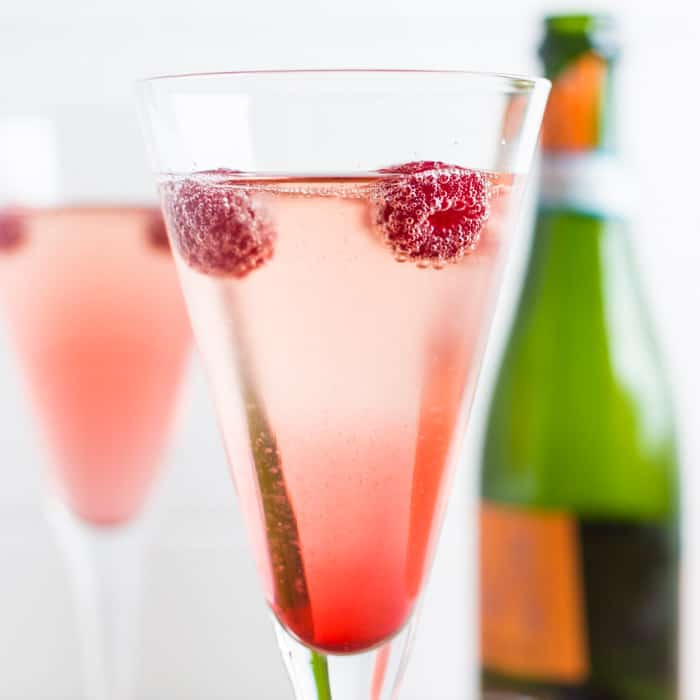 Raspberries floating on the surface of a glass of Kir Royale with prosecco