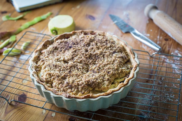 Blackberry and Apple Crumble Pie in a pie dish on a cooling traysurrounded by baking ingredients and equipment