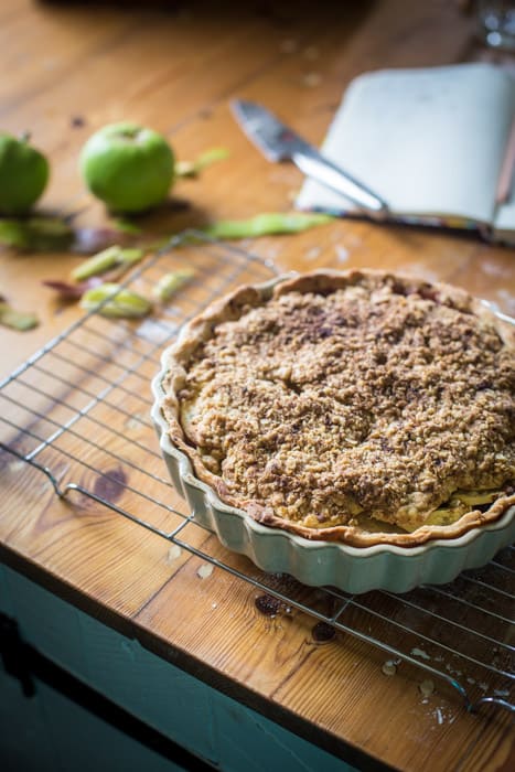 Blackberry and Apple Crumble Pie in a pie dish on a cooling traysurrounded by baking ingredients and equipment