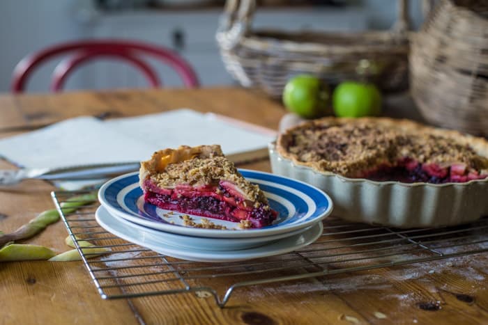 Blackberry and Apple Crumble Pie in a pie dish with 1 slice on a blue and white plate