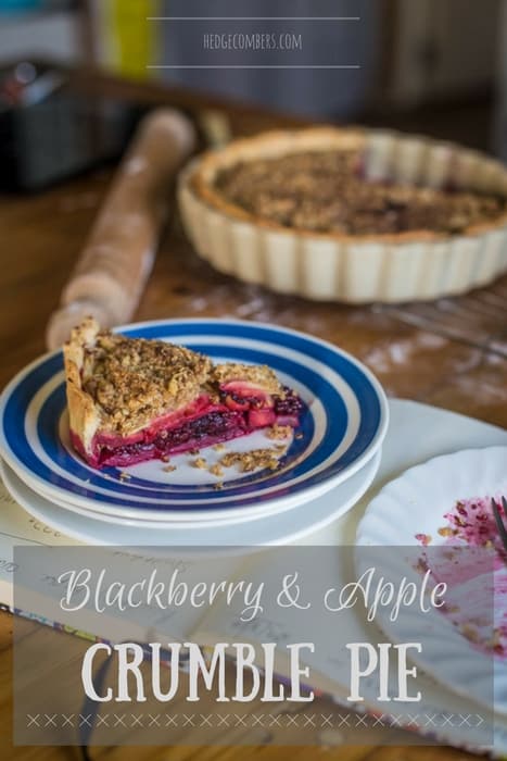 A rustic kitchen counter with Blackberry and Apple Crumble Pie, a rolling pin and an empty plate