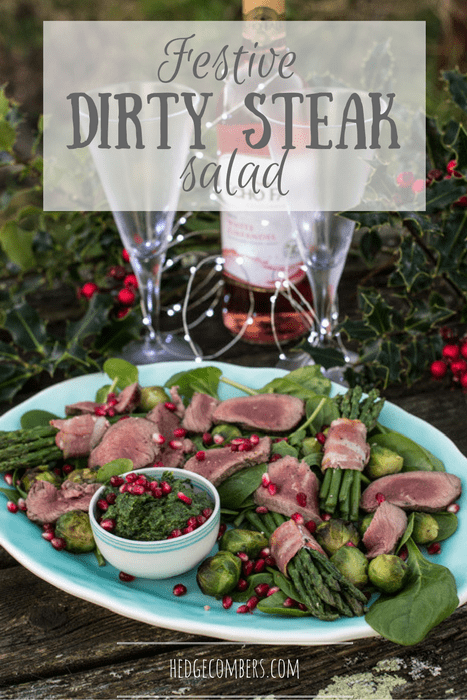Festive Dirty Steak Salad on a white plate with a bottle and 2 glasses surrounded by holly 