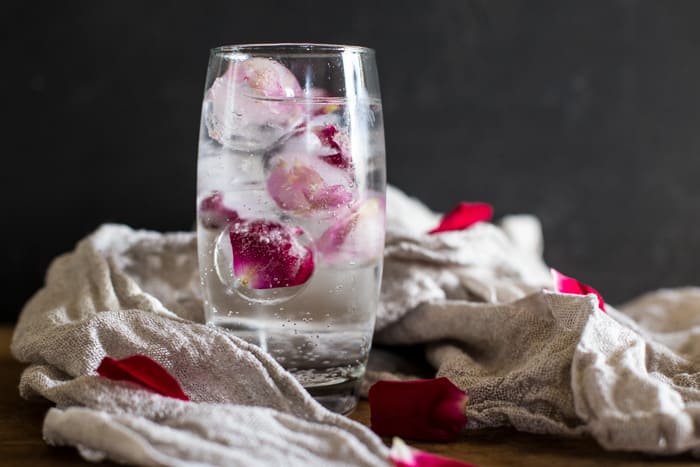 Rose and Elderflower Mocktailover ice in a tall glass with bottle of tonic and rose petals