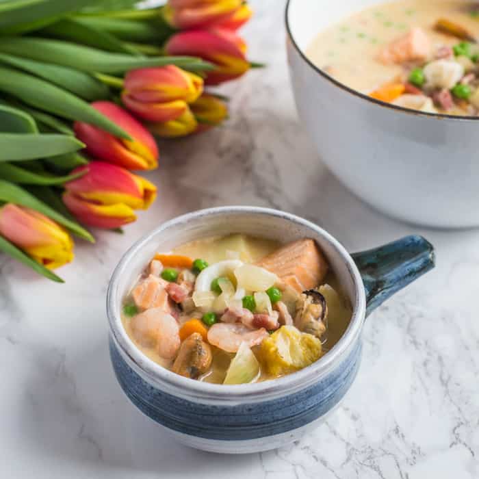 Dairy Free Seafood Chowder in bowls with tulips on a grey cloth