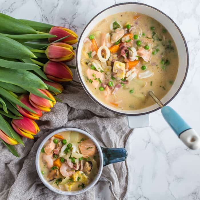 Dairy Free Seafood Chowder in bowls with tulips on a grey cloth