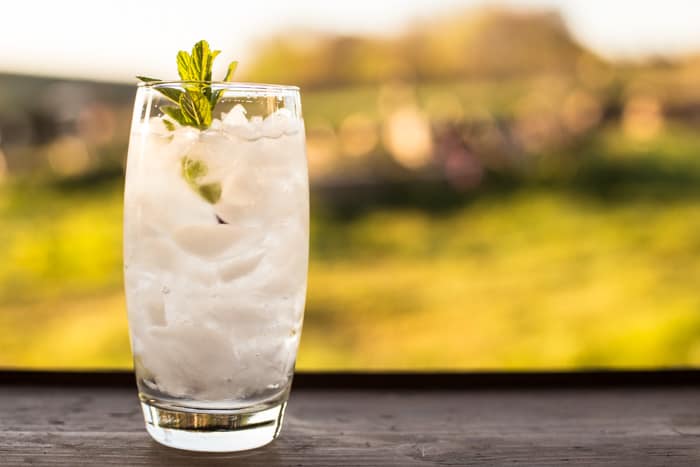 Elderflower & Vodka Cocktail Slush in a tall glasson an outdoor table .