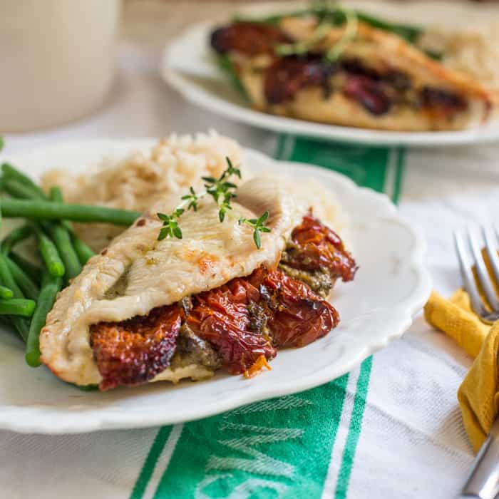 Sundried Tomato and Pesto Stuffed Chicken Breast on a white plate with basmati rice and green beans