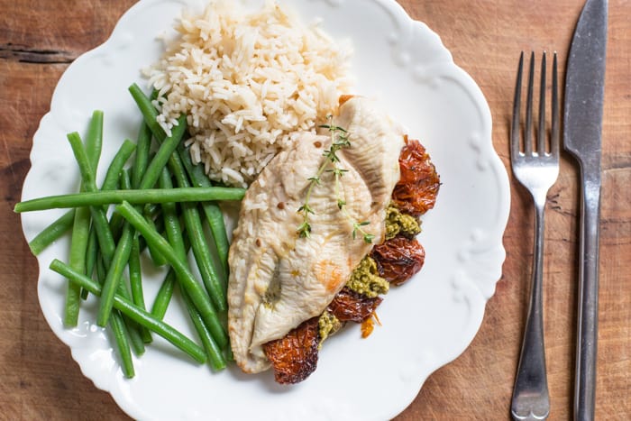 Sundried Tomato and Pesto Stuffed Chicken Breast on a white plate with basmati rice and green beans