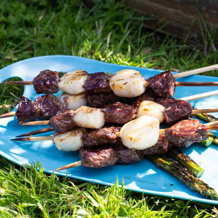 blue plate with steak and scallops kebab skewers and asparagus