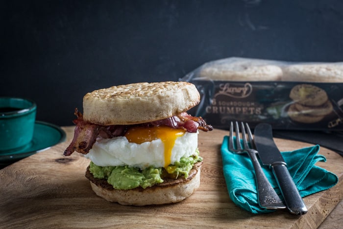 Breakfast Crumpet Burger on a wooden board with a knife and fork and a cup of coffee