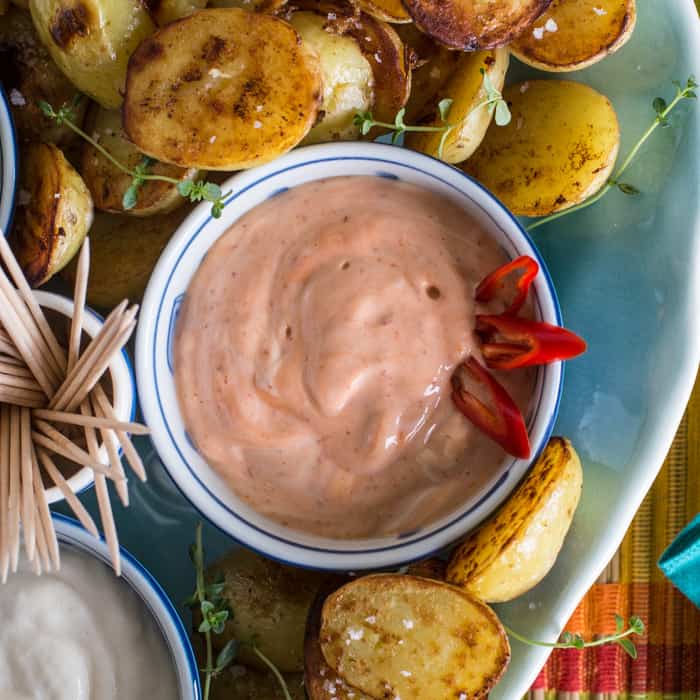 little blue oand white bowl fill with spicy harissa mayo and surrounded by crispy saute potatoes