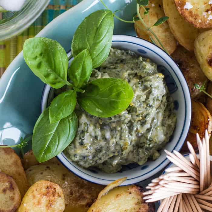 small bowl in a platter of saute fried potatoes filled with a homemade pesto mayonnaise