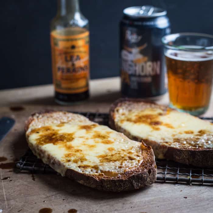 Cheese on toast, glass of beer and bottle of Worcester sauce