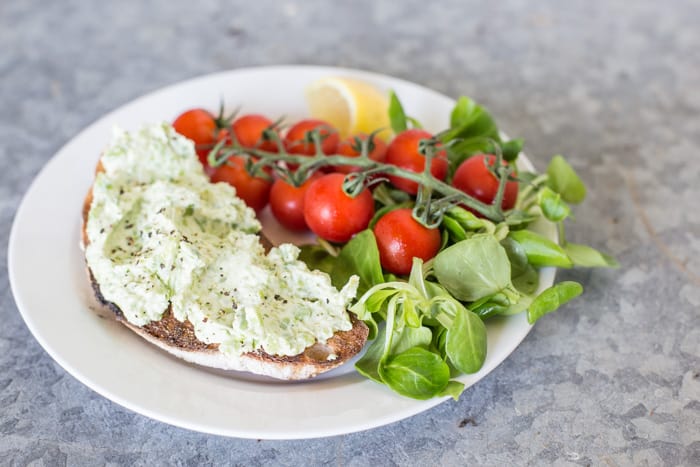 Broad Bean and Goats Cheese Bruschetta on a white plate with vine Tomatoes