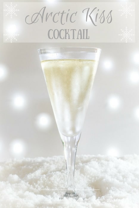 Champagne flute with light coloured cocktail on a bed of snow with bokeh background