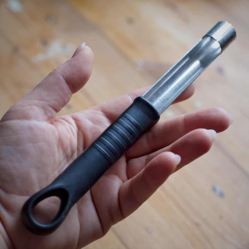 Woman holding a black handled stainless steel apple corer