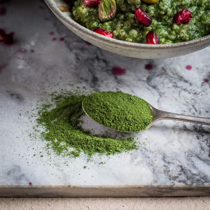 white and grey marble background with a teaspoon of organic green kale powder 