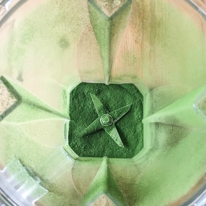 overhead shot into a blender with fine, bright green powder in the bottom