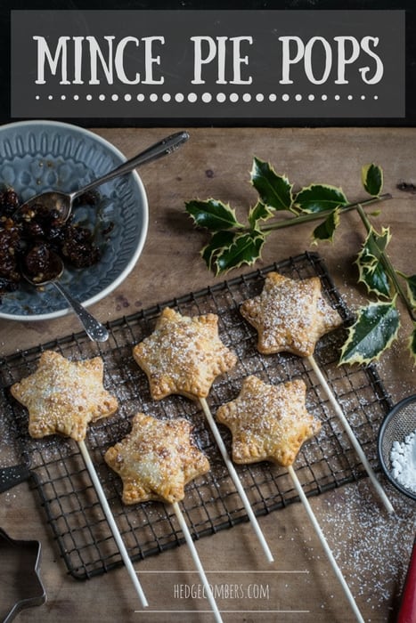 Mince Pie Pops on a cooling tray sprinkled with icing sugar beside a dish of mincemeatand a sprig of holly