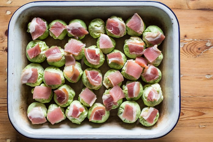 smashed Roast Sprouts with Bacon and Chestnuts in a roasting dish ready to cook